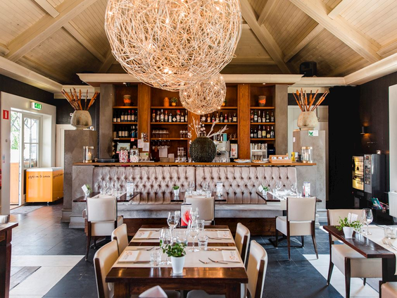 Het stijlvolle interieur van het parkrestaurant De Zoete Zoen op Landal Cauberg, met een grote kroonluchter en netjes gedekte tafels.