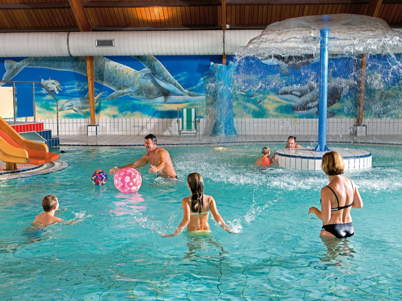 Kinderen en gezinnen spelen en spetteren in het overdekte zwembad van Landal Coldenhove met een waterpaddenstoel.