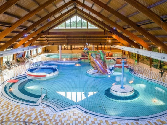Overzicht van het grote overdekte zwemparadijs van Landal Coldenhove met een glijbaan, kinderbad en bubbelbad.