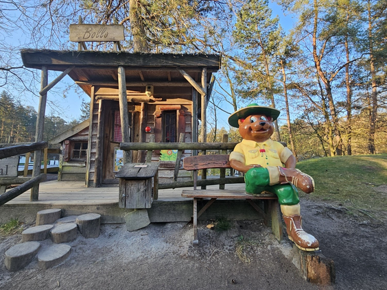 Bollo de Beer zit op een bankje in de avontuurlijke buitenspeeltuin van Landal Coldenhove op de Veluwe.