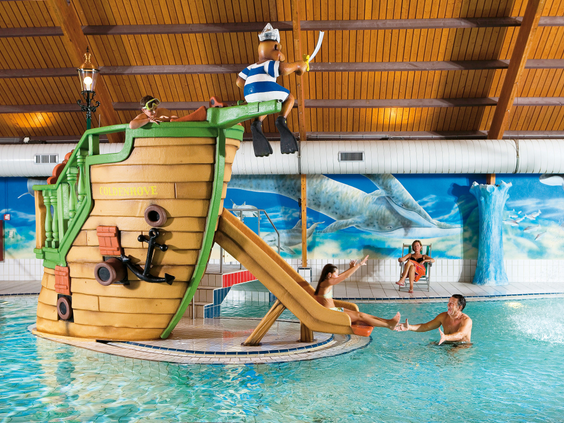 Kinderen spelen in het kinderbad op het houten piratenschip met een kleine glijbaan in het zwembad van Landal Coldenhove.