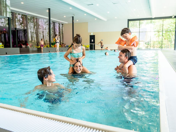 Gezin met kinderen speelt en lacht in het overdekte binnenzwembad van Landal de Vers in Noord-Brabant.