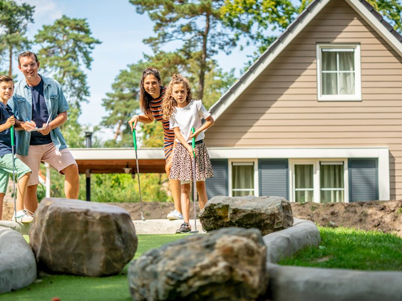Familie speelt een potje midgetgolf op de avontuurlijke baan met rotsen bij een bungalow op Landal De Vers.