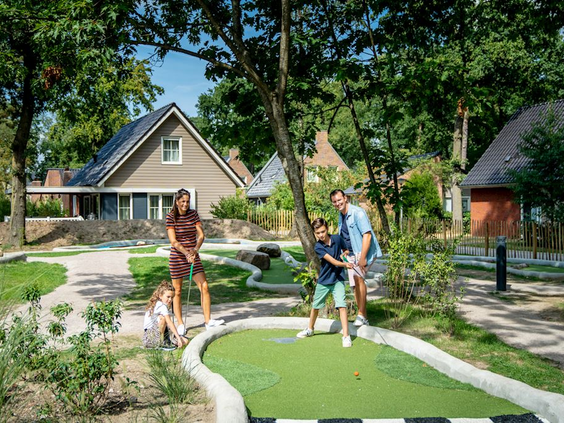 Familie met twee kinderen speelt een potje midgetgolf op de avontuurlijke golfbaan van Landal De Vers.