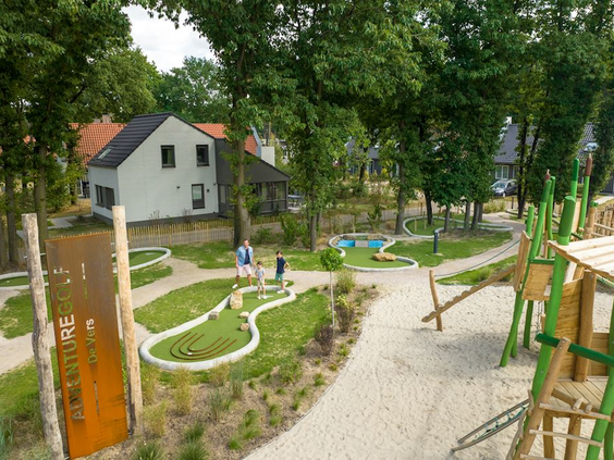 Overzicht van de faciliteiten op Landal De Vers, met de houten speeltuin en de midgetgolfbaan tussen de bomen.