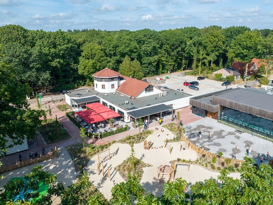 Luchtfoto van het centrumgebouw van Landal De Vers met het restaurant, terras en de grote natuurspeeltuin.