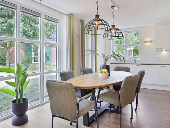 Stijlvol interieur van een bungalow op Landal De Vers met een ruime eethoek aan grote ramen die uitkijken op het groen.