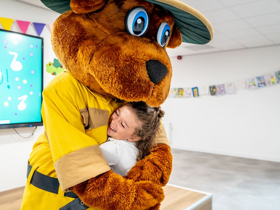 Klein meisje geeft een dikke knuffel aan Bollo de beer, de mascotte van Landal de Vers.