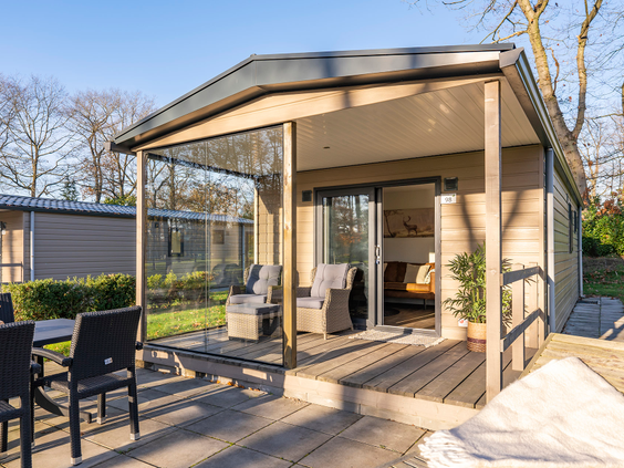 De luxe, overdekte houten veranda van een moderne lodge op Landal De Vlinderhoeve, met een comfortabele tuinset.