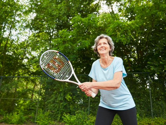 Een sportieve vrouw speelt een potje tennis op de outdoor tennisbaan van Landal De Wedderplassen.