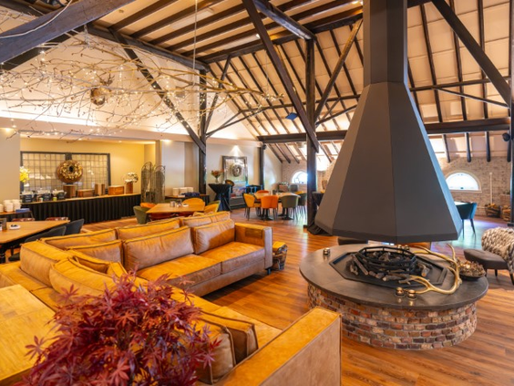 Het sfeervolle interieur van het restaurant op Landal De Wedderplassen, met een grote open haard in het midden.