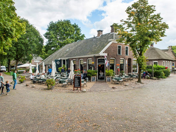 Een sfeervol terras bij een historische boerderij in het museumdorp Orvelte in Drenthe, waar bezoekers genieten van het weer.
