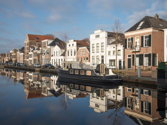 De historische gevels van grachtenpanden in de Drentse stad Meppel weerspiegelen in het kalme water van de gracht.