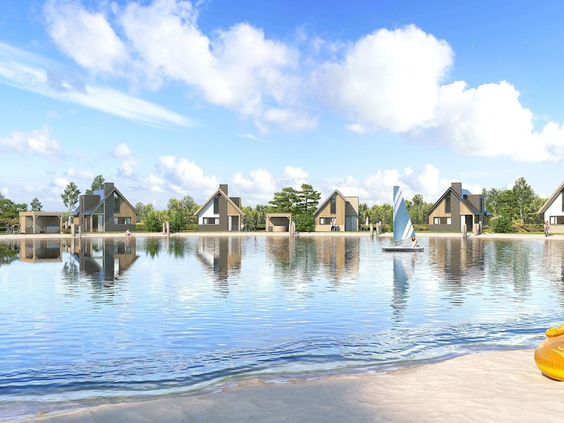 Uitzicht vanaf het strand over het recreatiemeer naar de luxe waterwoningen van vakantiepark Landal Drentse Lagune onder een blauwe hemel.