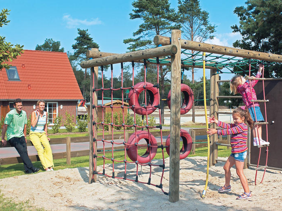 Kinderen klimmen en klauteren in de avontuurlijke buitenspeeltuin met een houten klimrek op Landal Dwergter Sand.