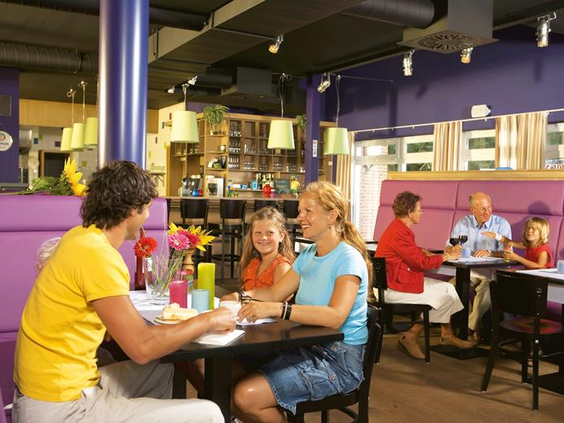 Een familie zit gezellig te eten in het sfeervolle restaurant van vakantiepark Landal Dwergter Sand.