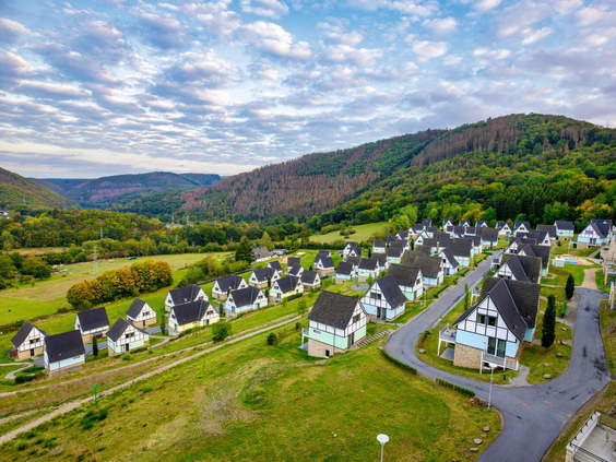 Luchtfoto van vakantiepark Landal Eifeler Tor in de Eifel, met de vakwerkhuizen en appartementen gelegen in een groen dal aan het stuwmeer.