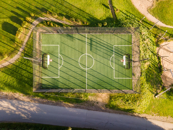 Luchtfoto van het multifunctionele sportveld (voetbalveld) op vakantiepark Landal Eifeler Tor, mooi gelegen in het groen.
