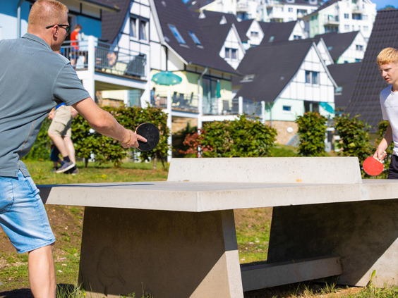 Vader en zoon spelen een potje tafeltennis op een buitentafel op vakantiepark Landal Eifeler Tor.