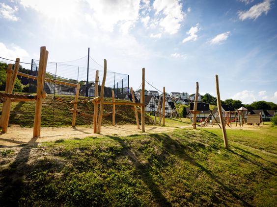 De avontuurlijke natuurspeeltuin van Landal Eifeler Tor, met een klimparcours van houten palen en touwen.