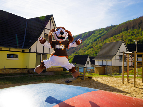 Mascotte Bollo de Beer springt vrolijk in de lucht op de grote airtrampoline in de speeltuin van Landal Eifeler Tor.