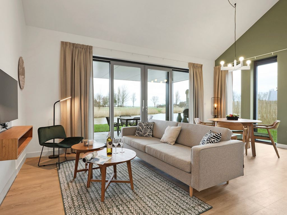 Lichte en ruime woonkamer met een comfortabele bank en grote ramen met uitzicht op buiten bij Landal Elfstedenhart.