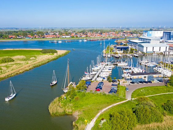 Luchtfoto van een grote jachthaven vol zeilboten en motorjachten aan de waterwegen van Friesland op een heldere, zonnige dag.