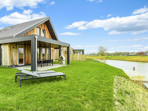 Ruim vakantiehuis met een grote tuin en ligbedden direct aan het water op vakantiepark Landal Elfstedenhart in Friesland.