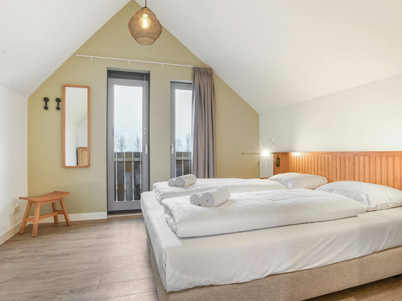 Sfeervolle en lichte slaapkamer met een opgemaakt tweepersoonsbed in een vakantiehuis op Landal Elfstedenhart in Friesland.