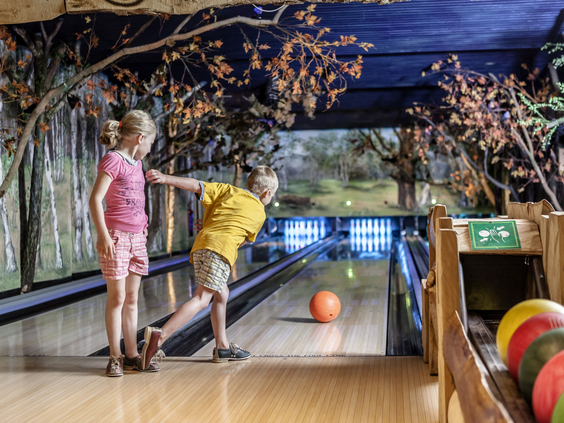 Een jongen en een meisje zijn aan het bowlen op de sfeervolle bowlingbaan in het indoorspeelparadijs van Landal Heideheuvel.