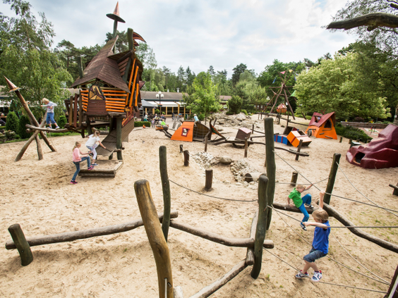 Overzicht van de grote avontuurlijke buitenspeeltuin van Landal Heideheuvel met zand, water en diverse speeltoestellen.