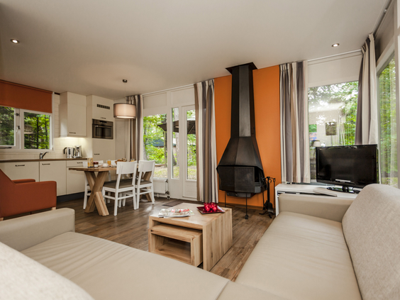 Het sfeervolle interieur van een comfortabele bungalow op Landal Heideheuvel met een moderne open haard, zithoek en open keuken.
