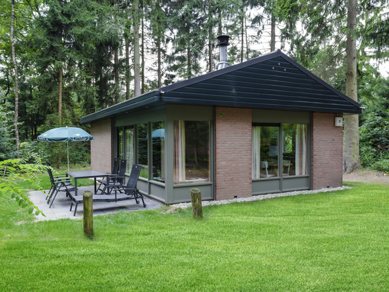 De buitenkant van een vrijstaande bungalow met terras, gelegen midden in de bossen op vakantiepark Landal Heideheuvel.
