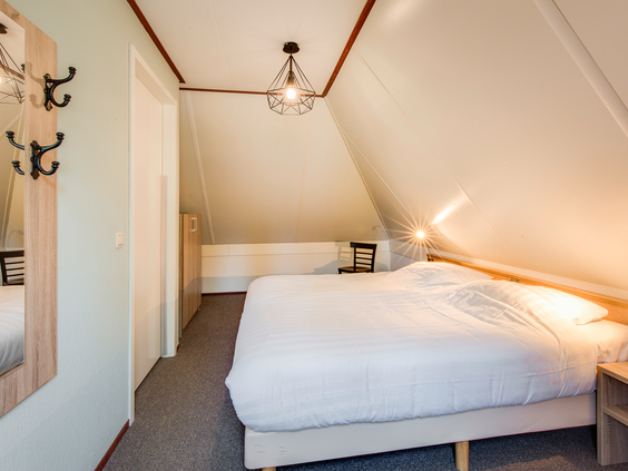 Een sfeervolle en ruime ouderslaapkamer met een comfortabel opgemaakt tweepersoonsbed in een bungalow op Landal Hellendoornse Berg.