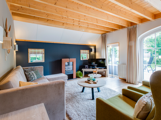 De modern ingerichte woonkamer van een bungalow op Landal Hellendoornse Berg met een comfortabele zithoek en uitzicht naar buiten.