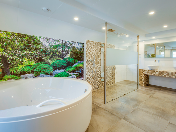 Een luxe wellness badkamer in een bungalow op Landal Hellendoornse Berg, met een groot rond bubbelbad en een aparte inloopdouche.