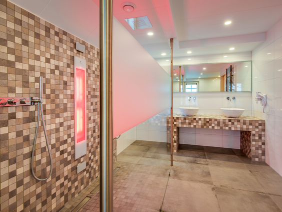 Een moderne wellness badkamer in een bungalow met een ruime inloopdouche die is uitgerust met een infrarood saunapaneel.