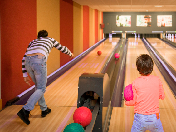 Een vader en zoon zijn aan het bowlen op een van de speciale kinderbowlingbanen op vakantiepark Landal Hellendoornse Berg.