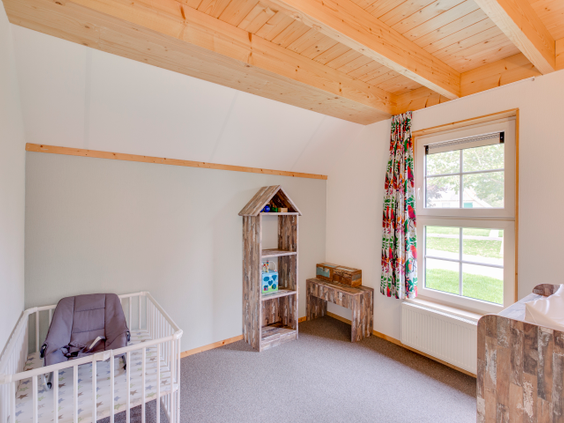 Een babykamer in een kinderbungalow op Landal Hellendoornse Berg, ingericht met een babybedje, commode en wipstoeltje.
