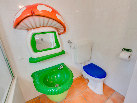 Een speciale kinderbadkamer in een bungalow op Landal Hellendoornse Berg, met een kindertoilet en een wasbak en spiegel in de vorm van een paddenstoel.