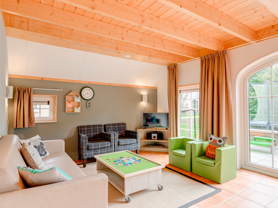 De woonkamer van een kinderbungalow op Landal Hellendoornse Berg, ingericht met een speciale speeltafel en kinderstoeltjes.