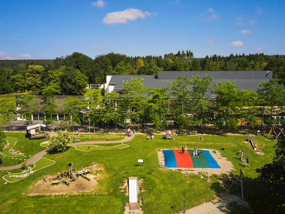 Overzicht van de grote avontuurlijke buitenspeeltuin bij Landal Hochwald, met houten klimtoestellen, trampolines en zandbakken.