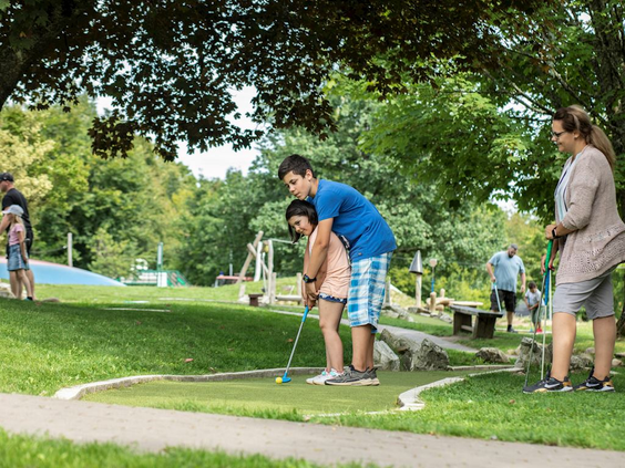 Een familie speelt samen een potje midgetgolf (minigolf) op de buitenbaan bij Landal Hochwald.