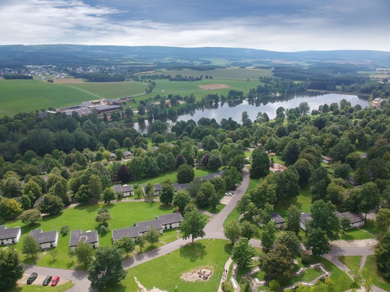 Luchtfoto van vakantiepark Landal Hochwald, met de bungalows verspreid in het groene landschap naast het grote stuwmeer.