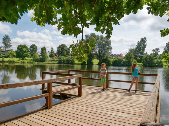Twee kinderen staan op een houten vlonder aan de rand van het grote stuwmeer bij vakantiepark Landal Hochwald.