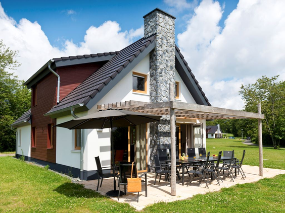 De buitenkant van een vrijstaande, moderne bungalow met terras op een grasveld bij Landal Hochwald.