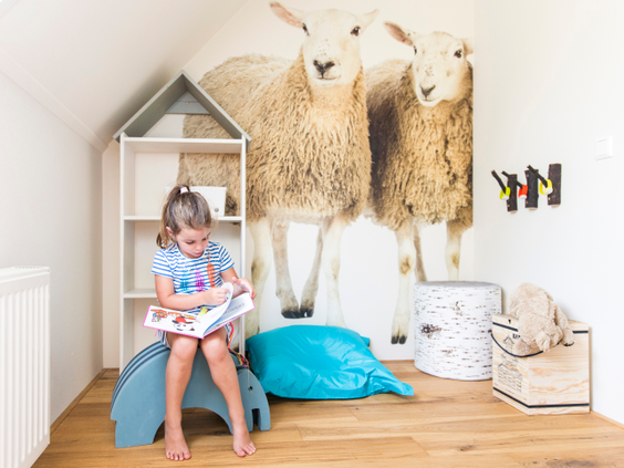 Een jong meisje zit een boekje te lezen in de speciaal ingerichte Kinderboerderij-kinderkamer in een van de boerderijen op Landal Hof van Saksen.