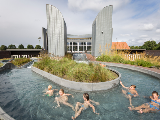 Een groep kinderen ontspant en speelt in het buitenste gedeelte van de wildwaterbaan bij het hoofdgebouw van Landal Hof van Saksen.