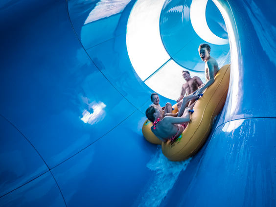 Een groep mensen in een vierpersoonsband suist door de enorme trechter van de waterglijbaan Bombo in het zwemparadijs van Landal Hof van Saksen.