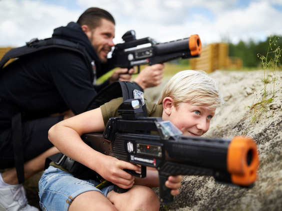 Een close-up van een jongen en een meisje die geconcentreerd met hun laserguns richten terwijl ze zich verstoppen tijdens een potje lasergame bij Landal Hof van Saksen.